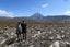 Brother and sister pose side by side in the alpine landscape with Tongariro visible in the distance